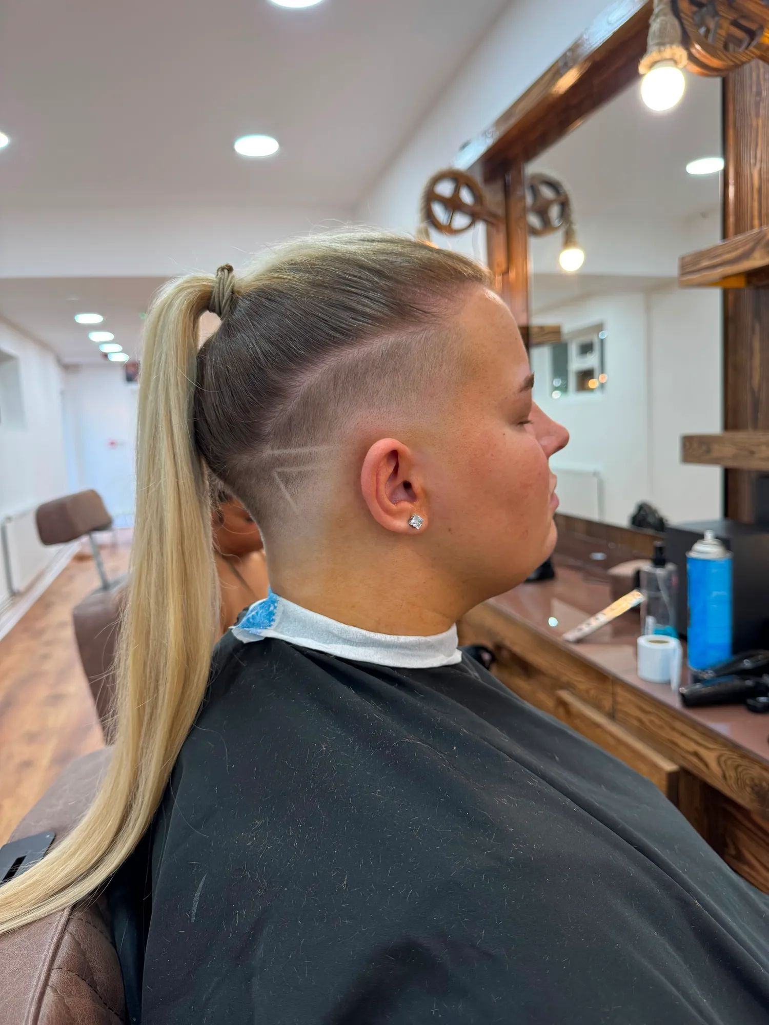 Shaved undercut design with a long blonde ponytail